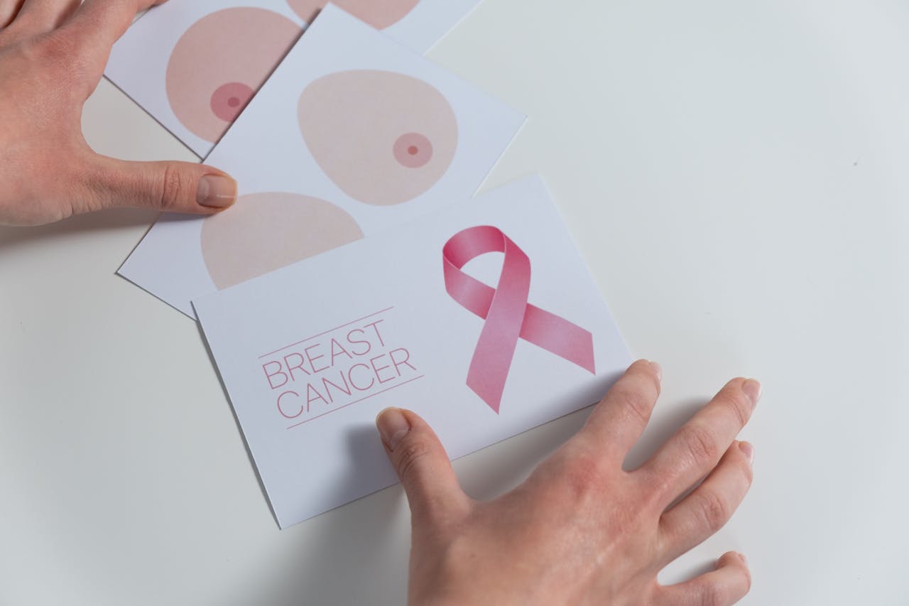 Hands arranging breast cancer awareness cards with a pink ribbon symbol.