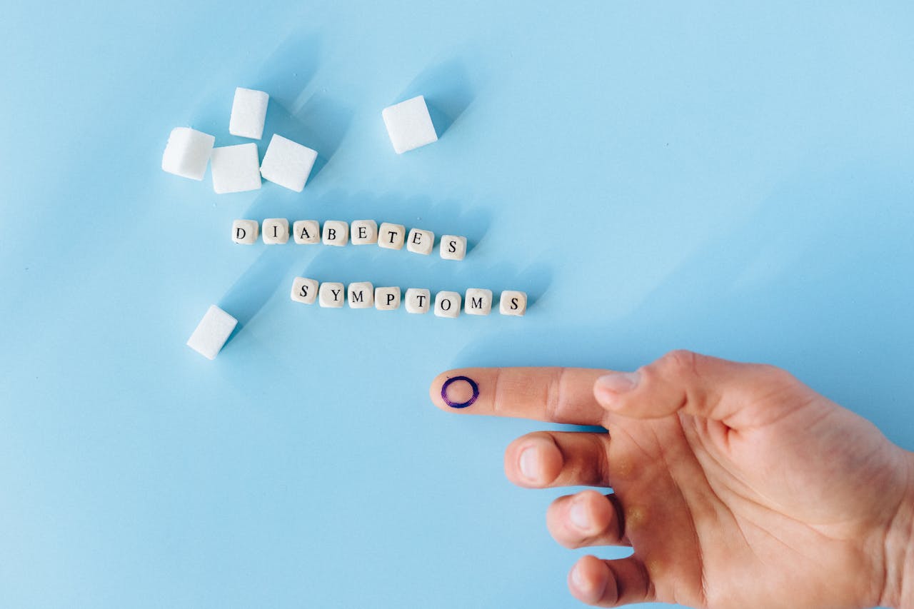Services Close-up of a hand with marked finger pointing to diabetes symptoms text and sugar cubes.