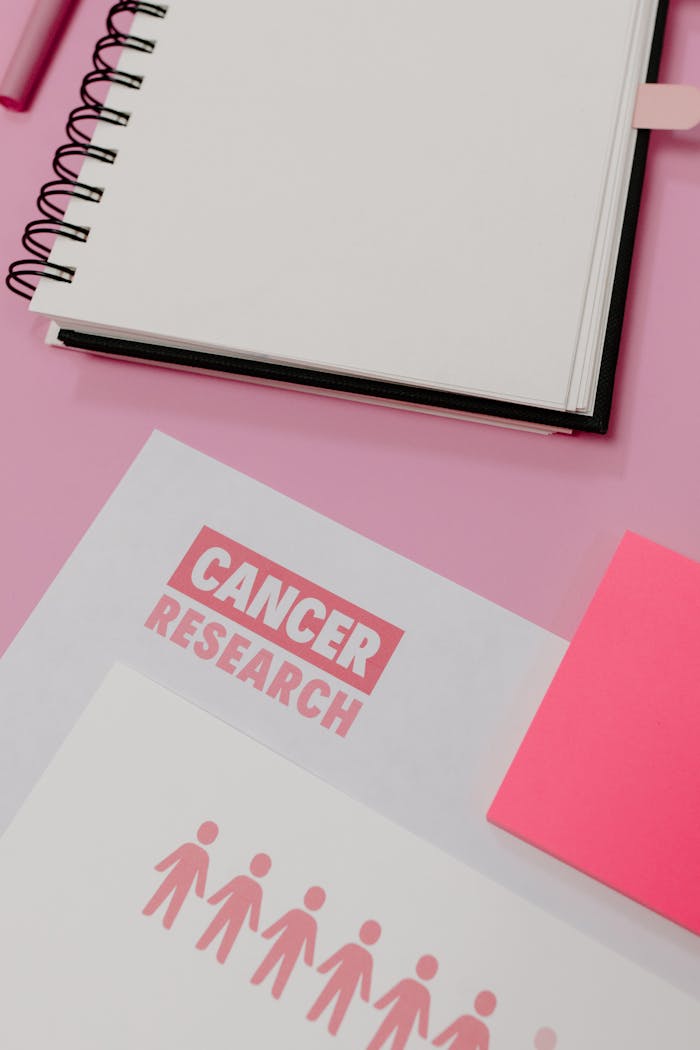 Flat lay of cancer research materials on a pink background highlighting awareness